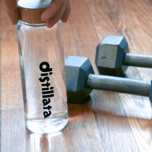 glass distillata water bottle next to silver weights