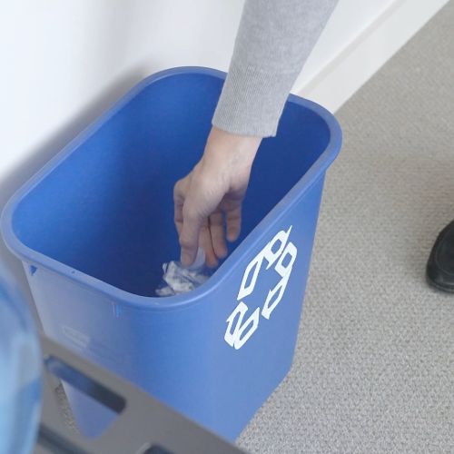 placing a plastic bottle in a recycling bin in an office setting