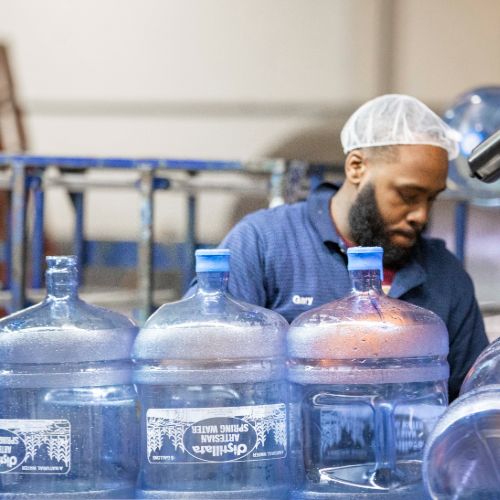 distillata warehouse employee working on 5 gallon bottling line