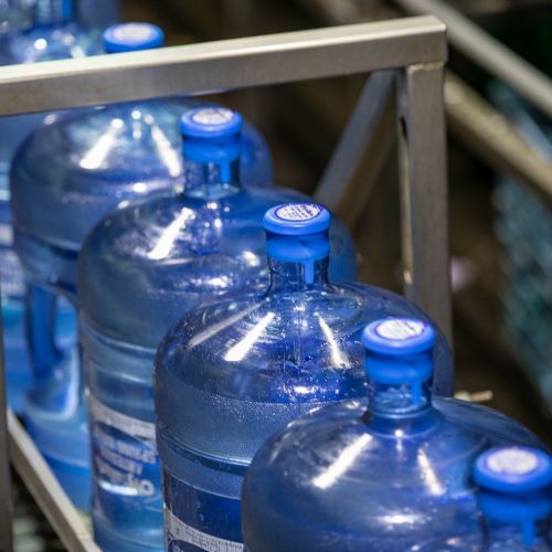 distillata 5 gallon water bottles with blue caps on production line