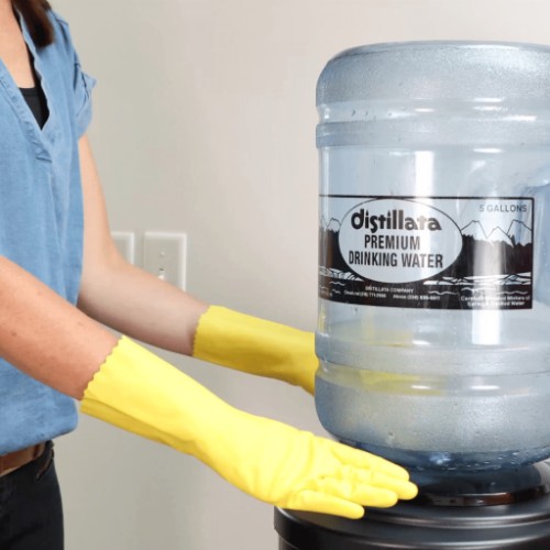 removing 5-gallon bottle from water cooler with yellow gloves