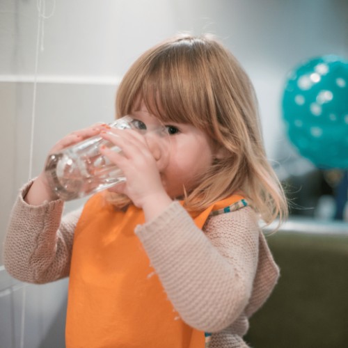 child drinking water from a clear glass