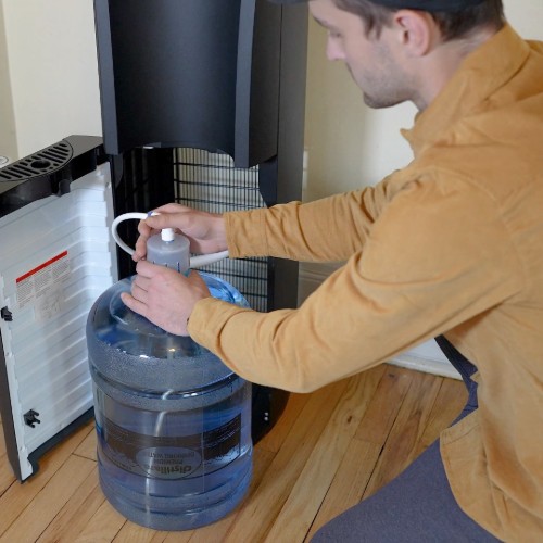 man loading a 5 gallon water bottle in a bottom load water cooler