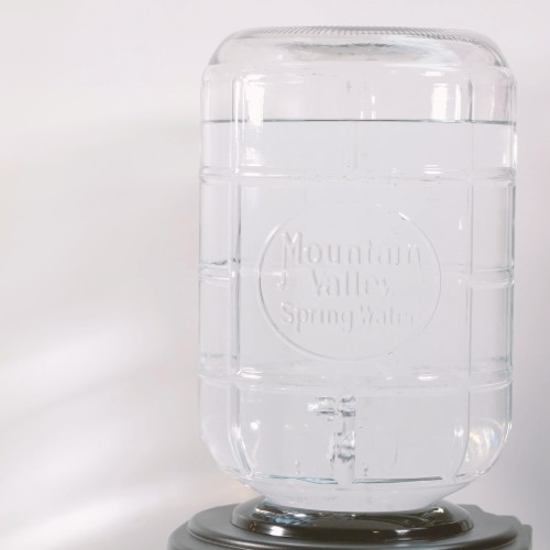 glass mountain valley spring water bottle on a water dispenser with bubbles in water