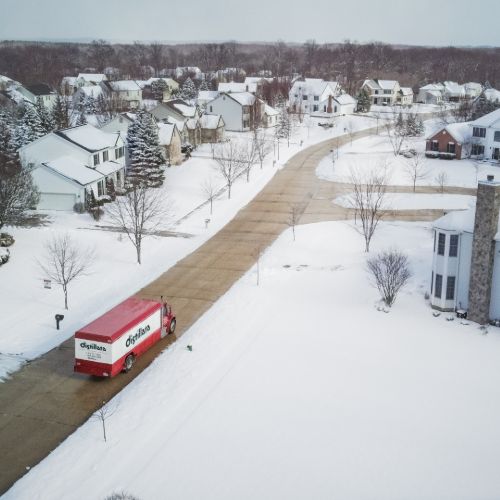 distillata truck driving through neighborhood in snow