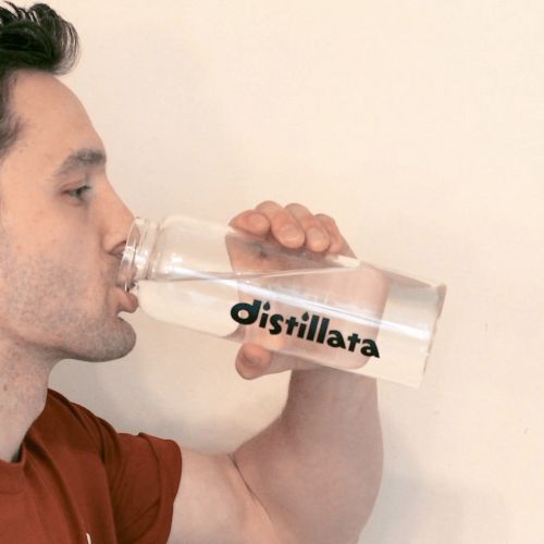 drinking water from a glass distillata water bottle
