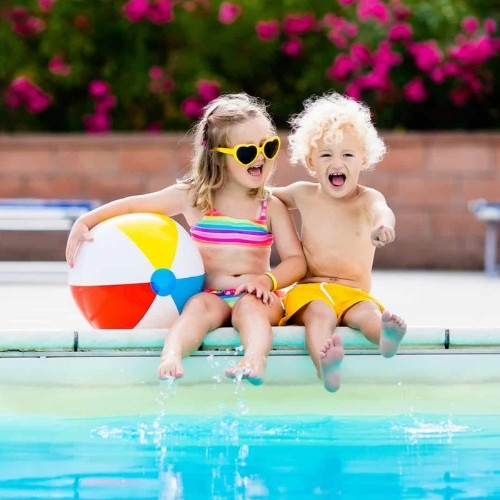 kids sitting on the edge of a swimming pool splashing the waterr