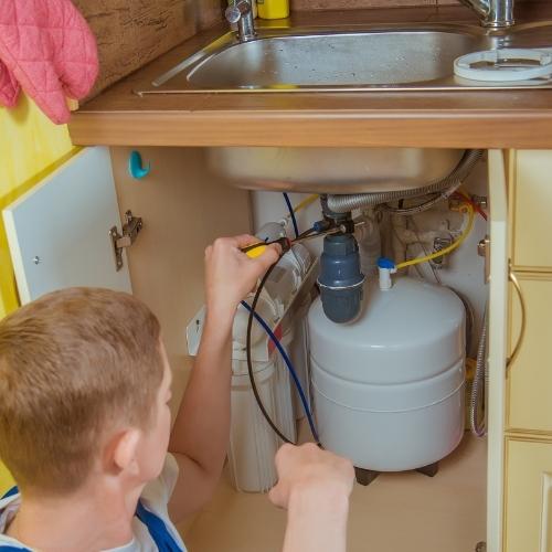 man installing an under sink water filter