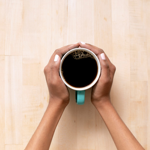 hands holding turquoise mug filled with black coffee