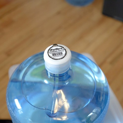 top of 5 gallon Distillata water bottle with a white