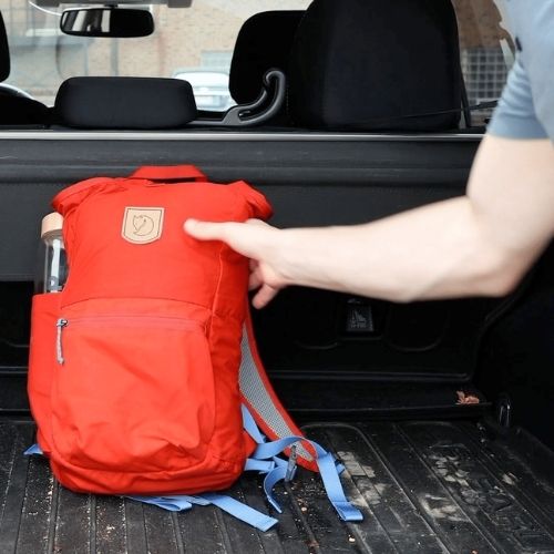 putting orange backpack in back of car