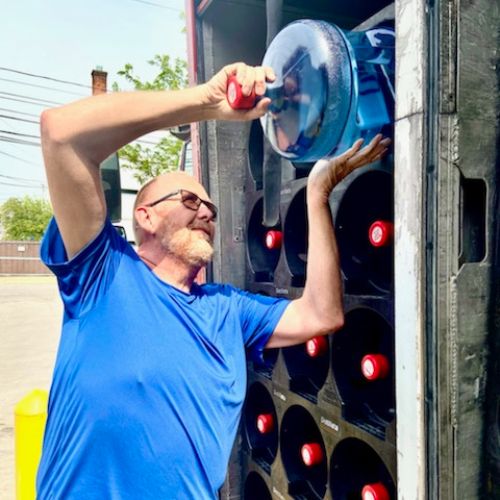 Distillata delivery driver pulling 5-gallon bottle out of truck
