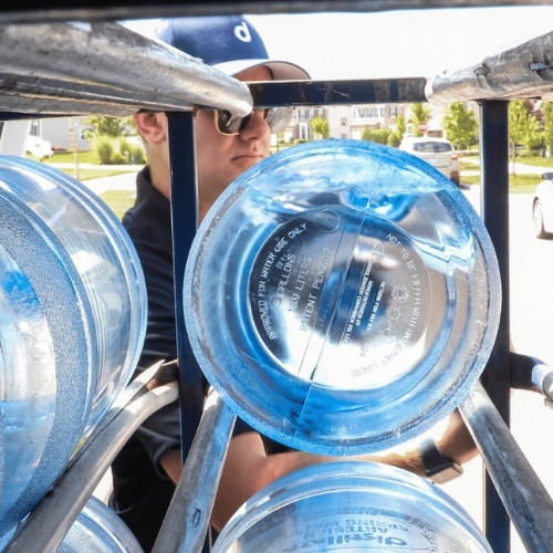 Distillata delivery driver removing 5-gallon water bottle from rack in Aurora, Oh