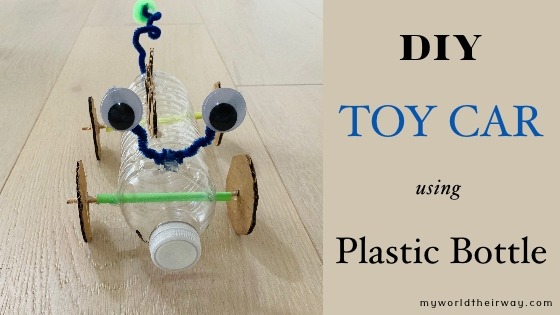 A photo of a DIY toy car made from a plastic bottle, cardboard, pipe cleaners, and googly eyes. The car has four wheels, a body made from a plastic bottle, and pipe cleaner antennas.