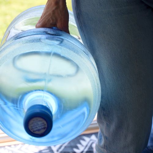 Close-up of a hand carrying a large water jug.