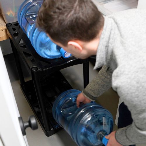 Man loading water jugs onto a storage rack.